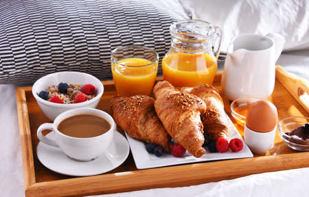 A tray with breakfast on a bed in a hotel room.の写真素材