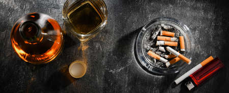 Composition with a bottle of whiskey, an ashtray and cigarettes.の写真素材