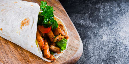 Tortilla with chicken and fresh vegetables on a cutting boardの写真素材