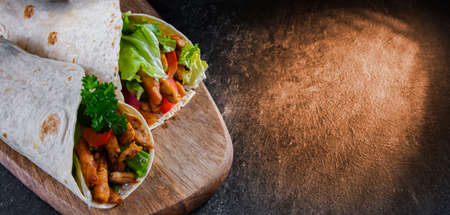 Tortilla with chicken and fresh vegetables on a cutting boardの写真素材