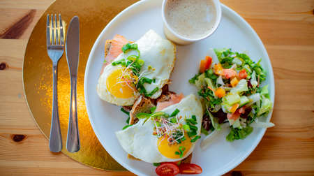 Breakfast with fried eggs on toasts on a restaurant tableの写真素材