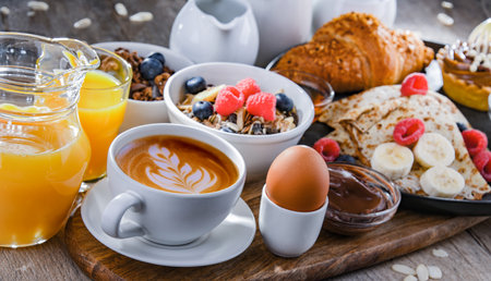 Breakfast served with coffee, orange juice, pancakes, croissants, cereals and fruitsの写真素材