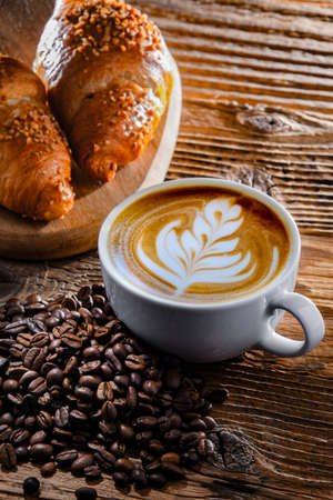 Composition with a cup of coffee and two croissants on an old wooden tableの写真素材
