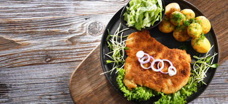 Pork breaded cutlet coated with breadcrumbs served with potatoes and cabbage