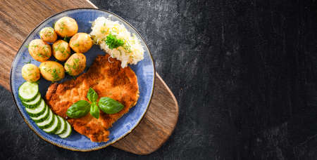 Pork breaded cutlet coated with breadcrumbs served with potatoes and cabbageの写真素材