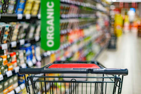 A shopping cart by a store shelf in a supermarketの写真素材