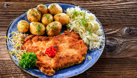 Pork breaded cutlet coated with breadcrumbs served with potatoes and cabbageの写真素材