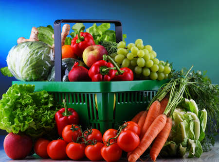 Fresh organic fruits and vegetables in plastic shopping basket.の写真素材