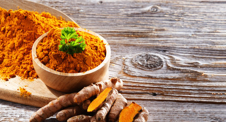 Composition with a bowl of ground turmeric and its fresh rhizome.の写真素材