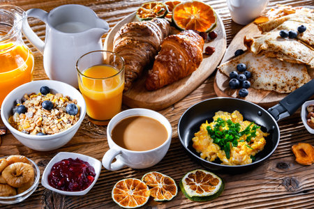 Breakfast served with coffee, orange juice, scrambled eggs, cereals, pancakes and croissants.の写真素材