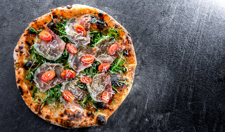 Pizza Italiana served with ham, cheese, tomatoes and rucola.の写真素材