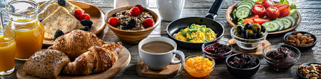 Breakfast served with coffee, orange juice, croissants, cereals, scrambled eggs and pancakes.