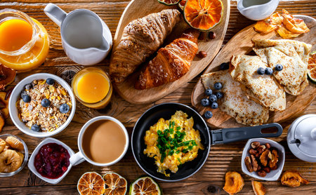 Breakfast served with coffee, orange juice, scrambled eggs, cereals, pancakes and croissants.の写真素材