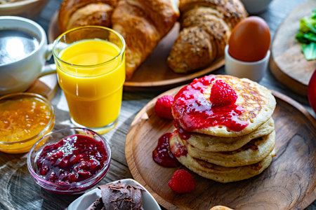 Breakfast served with coffee, orange juice, pancakes, croissants, cereals and eggs.