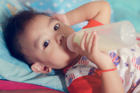 baby boy with a milk bottle at bedroomの写真素材