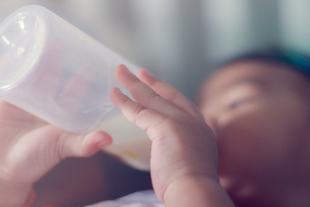 baby boy with a milk bottle at homeの写真素材