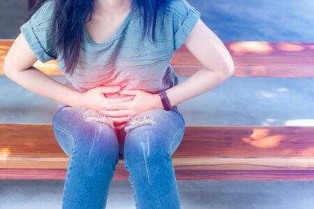 Young Woman With Stomach Ache sitting on staircase.の写真素材