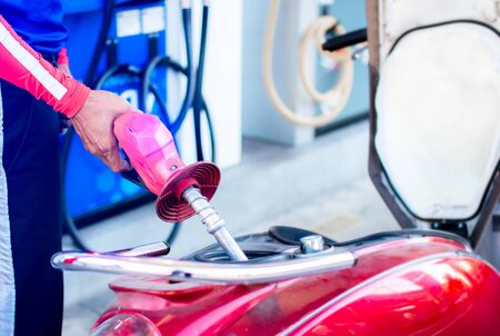 Hand fuel nozzle in pouring to motorcycle at gasoline pistol pump.の写真素材