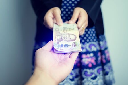 Hand of a businessman giving money to his partner, bribery and corruption concepts.