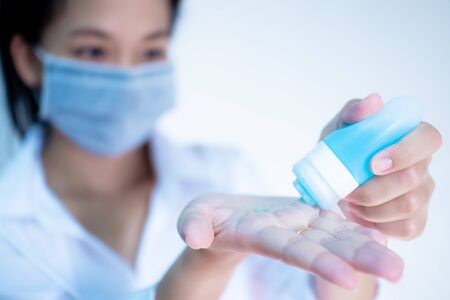 woman wearing hygienic protective mask using wash hand sanitizer alcohol  standing on white background with copy space ,daily protection from corona virus or COVID-19 concept.の写真素材