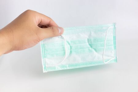 Hand that holds the masks on the white background. Health masks to prevent germs, viruses, and Covid-19.の写真素材