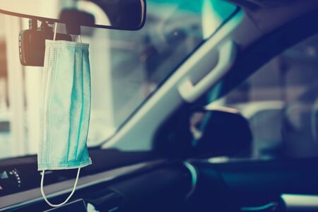 Hygienic masks hanging on the windshield on the inside of the car, where the sunlight comes...