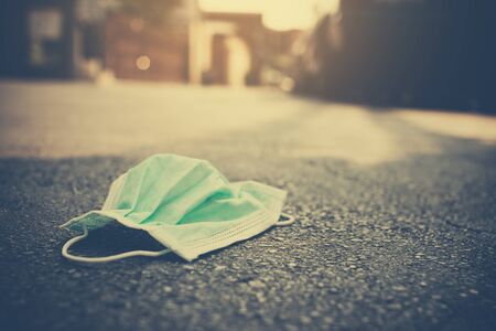 The medical masks used for the anti-corona virus that were used were left on the road. Improper removal of the mask caused Covid-19 to spread in a plastic bag and seal the bag before putting in trash.の写真素材