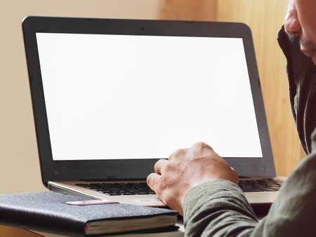 Man's hand using laptop with blank screen on table in home