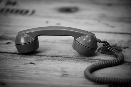 Old black phone with dust and scratches on wooden retro floorの写真素材