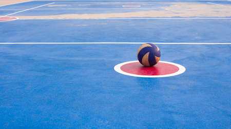 An old volleyball ball that was left in the center of the red circle around the ground was four blue.の写真素材