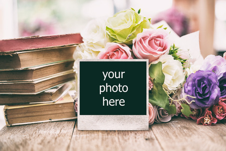 Blank vintage photo frame on wooden table with old books and flowers.Toned image.の写真素材