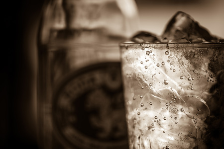 A glass of soda water with ice in sepia tone.Toned image,soft focus,film noir style.