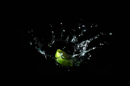 The object falls into the water until the sponge splits beautifully on a black background.の写真素材