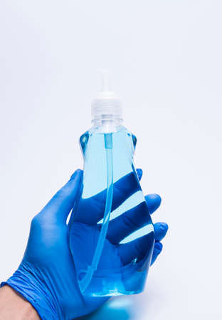 Hands wearing blue gloves are holding an alcohol bottle for cleaning duringの写真素材