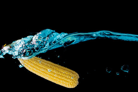 Corn pods fall into the water that is blue until the water is spread in waves, creating beautiful...
