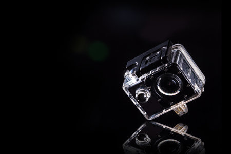 action cam is placed on a reflective area. With light shining from the side to the black backgroundの写真素材