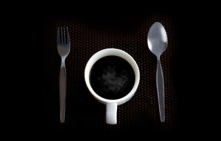 Hot coffee laid on a black plastic floor with a spoonの写真素材