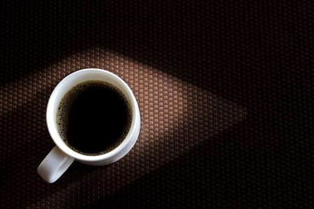 A white coffee mug placed on a brown plastic floorの写真素材