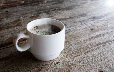 A cup of coffee on a wooden table in the morning lightの写真素材