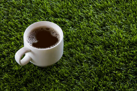 A white hot coffee cup placed on a green grassの写真素材