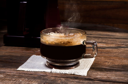 A cup of coffee on a wooden table in the morning lightの写真素材