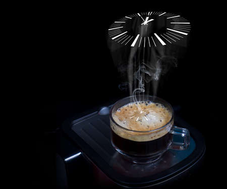 The smoke floated from the coffee cup as a clock. Hot espresso coffee in a clear glass Placed on a stainless steel floor with a black backgroundの写真素材