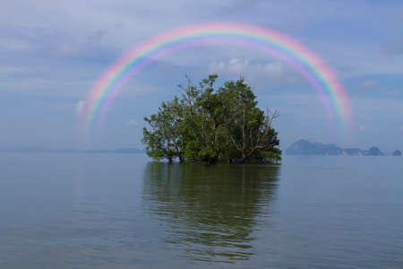 Rainbow over a small island in the middle of a bay in the morning sea.の写真素材