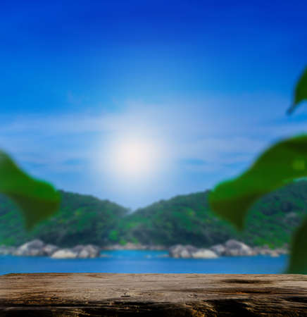 An empty wooden table has an empty space above a mountain backdrop. Sky, sea and mountain background blur For editing product displayの写真素材