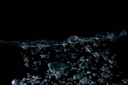 water waves with beautiful bubbles on a black background.の写真素材