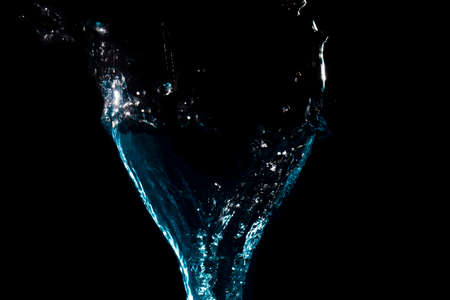 The object falls into the black water until a sponge splits beautifully on a black background.の写真素材