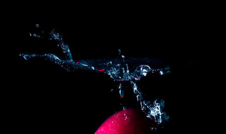 The object falls into the black water until a sponge splits beautifully on a black background.の写真素材