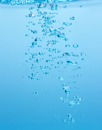 Various bubbles, sharp and blurry. Floating from the middle of the water up to the water surface...