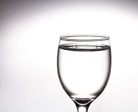 A tall glass, a glass of wine with clear water inside on a gray background.の写真素材