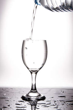 Pour the clear water into the wine glass until full, creating a slight air bubble in the glass, showing freshnessの写真素材